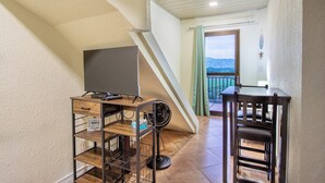 Una habitación con escritorio de madera, una silla, un ventilador y vistas al exterior.