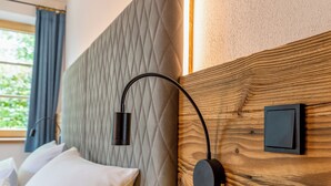 A neatly made bed with white linens and pillows, a wooden headboard, a bedside table, and a wall-mounted light fixture. - Suite Pfaffersee - barrier-free access with terrace and lake view (Chieming)