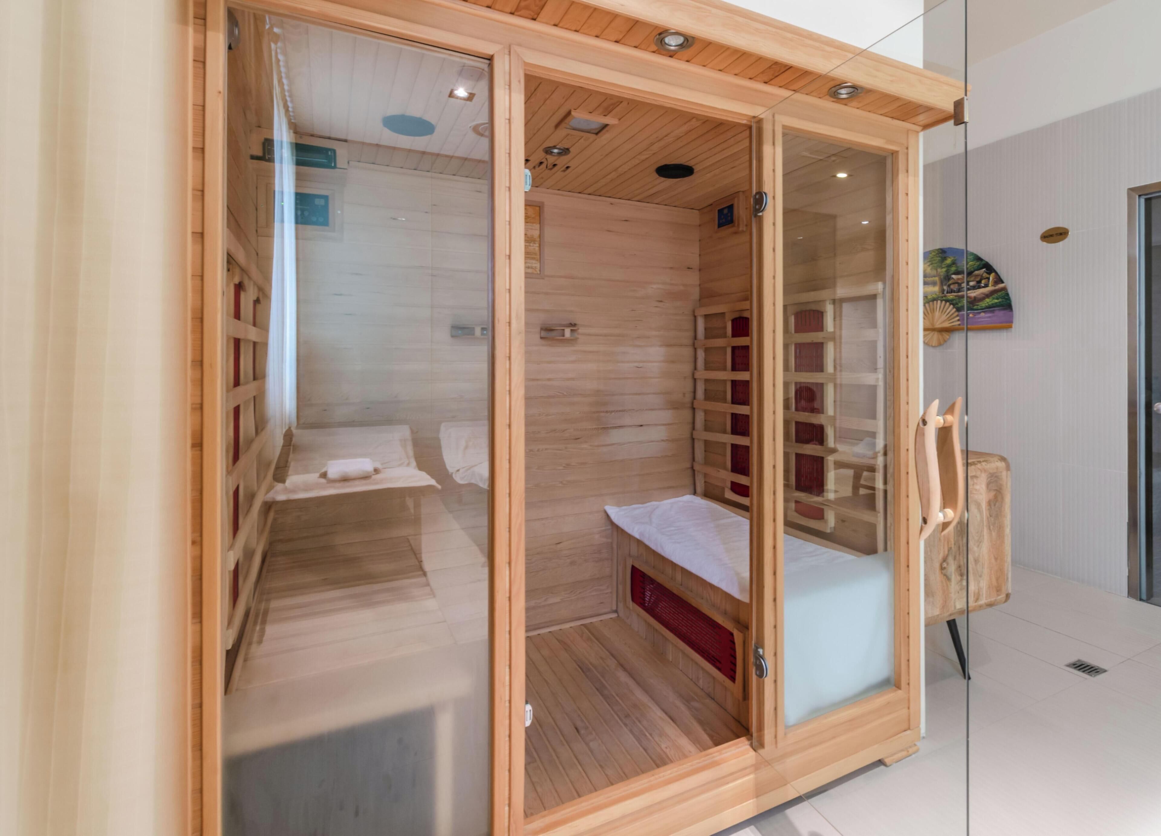 Una sauna moderna con pareti in legno e porta in vetro, dotata di una panca e un tavolino.