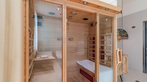 Una sala de sauna con paredes y bancos de madera, una puerta de vidrio y un banco de madera afuera.