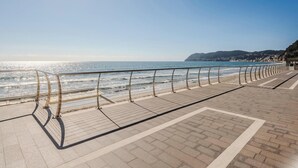 Un paseo marítimo con cielo despejado, una pasarela de madera y una barandilla de metal.