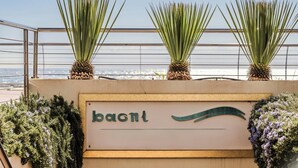 Un balcón con barandilla, un cartel que dice 'bagnit' y plantas.