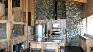Une cuisine rustique avec des meubles en bois, un mur en pierre et un îlot central doté de tabourets de bar.
