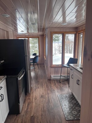 A kitchen with wooden floors, a refrigerator, a sink, and a window with a view of trees. - Spacious 5-bedroom resort with WiFi, AC in lovely Tenstrike (Tenstrike)