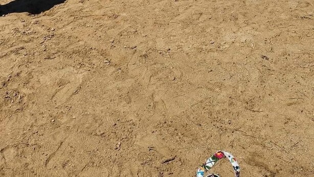 Une plage à l’eau d’un bleu cristallin, un bateau amarré sur le rivage et des gens qui profitent de la mer.