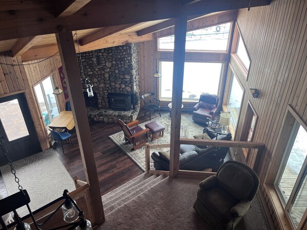 A cozy cabin interior with a stone fireplace, wooden walls, and large windows. - Spacious 5-bedroom resort with WiFi, AC in lovely Tenstrike (Tenstrike)