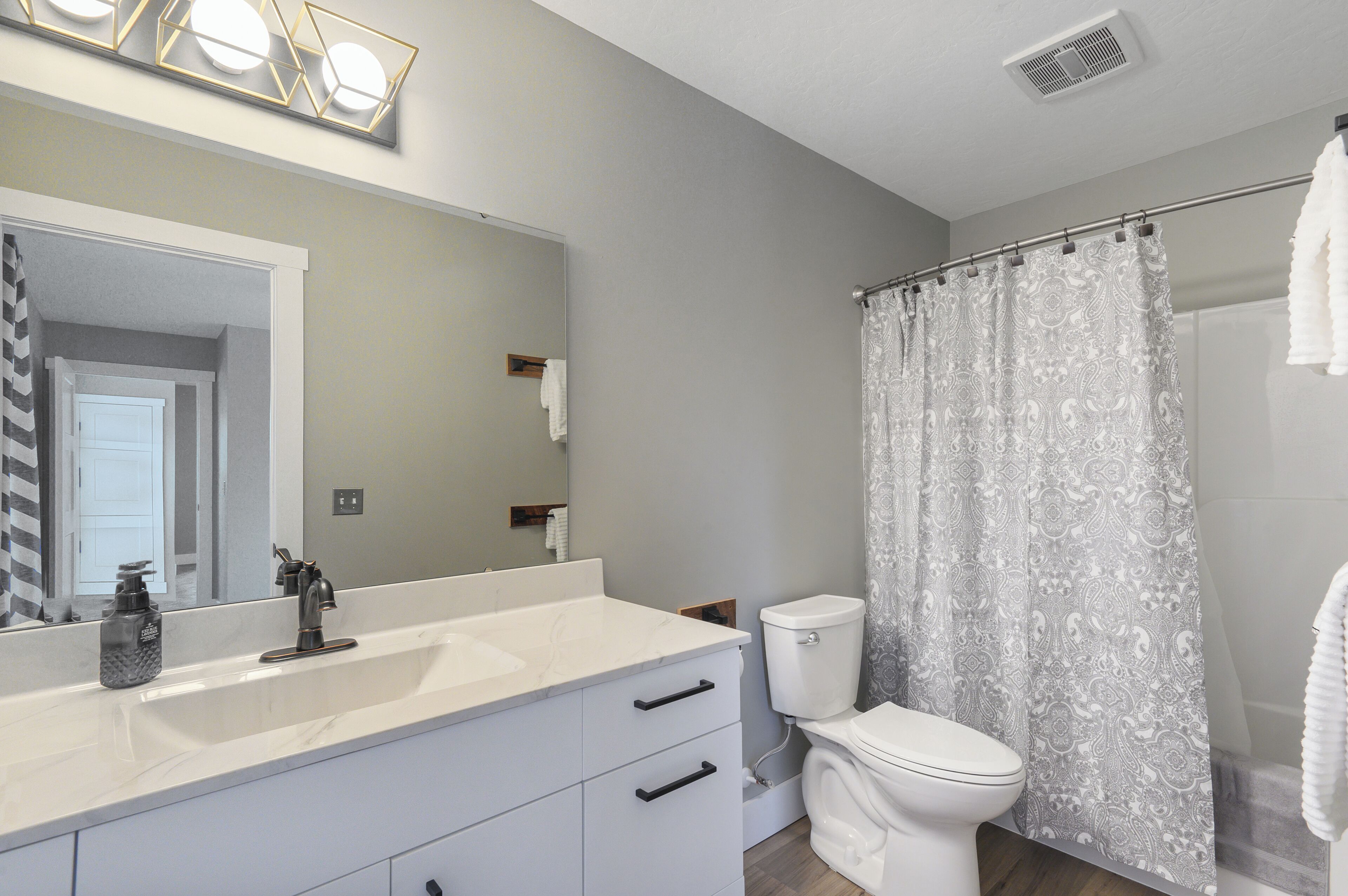A bathroom with a white sink, a toilet, and a shower curtain.