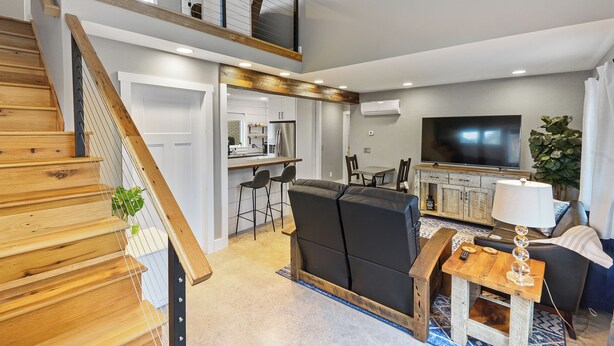 A modern living room with a staircase, a dining area, and a kitchen. - Apartment on Broadway St - K (Sugarcreek)