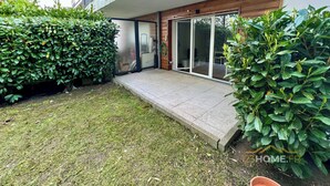 A modern house with a covered patio, a small garden, and a large sliding glass door leading to an outdoor seating area. - 123home- Garden & spa (Serris)