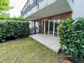 Una casa moderna con un porche cubierto, un pequeño jardín y un amplio ventanal corredera que da a un espacio de estar al aire libre.