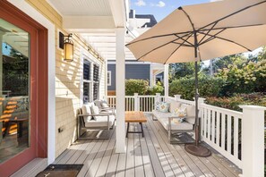 A covered porch with outdoor furniture, a wooden table, and a large umbrella.