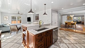 A spacious kitchen with a large island, wooden cabinets, and a modern pendant light.