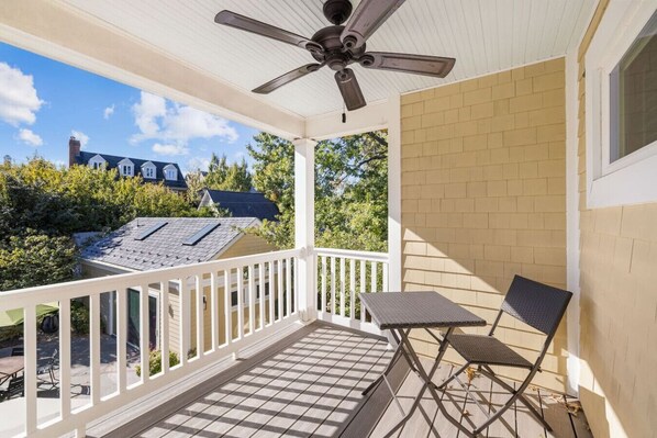 A covered porch with a ceiling fan, a table, and two chairs.