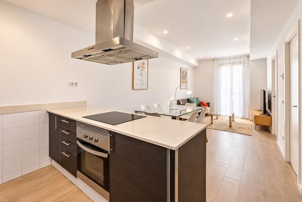 A modern kitchen with a central island, built-in oven, and stainless steel range hood.