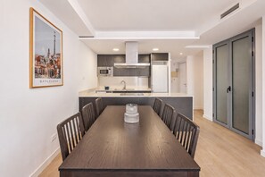 A modern kitchen with a central island, a dining table with chairs, and a framed picture on the wall. - Sweett | Symphonic Central 102 (Barcelona)