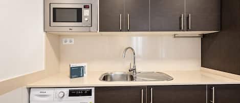 A kitchen with a microwave, sink, and washing machine.