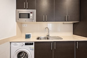 A kitchen with a microwave, sink, and washing machine. - Sweett | Symphonic Central 202 (Barcelona)