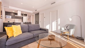 A modern living room with a grey sofa, yellow pillows, a glass coffee table, and a woven basket. - Sweett | Symphonic Central 202 (Barcelona)