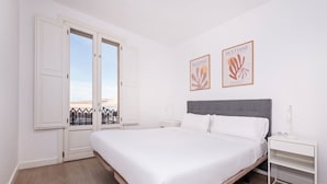 Une chambre à coucher avec un grand lit, une table de chevet, une commode et deux œuvres d’art encadrées accrochées au mur.