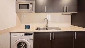 Une cuisine compacte équipée d’un four à micro-ondes, d’un évier et d’un lave-linge.