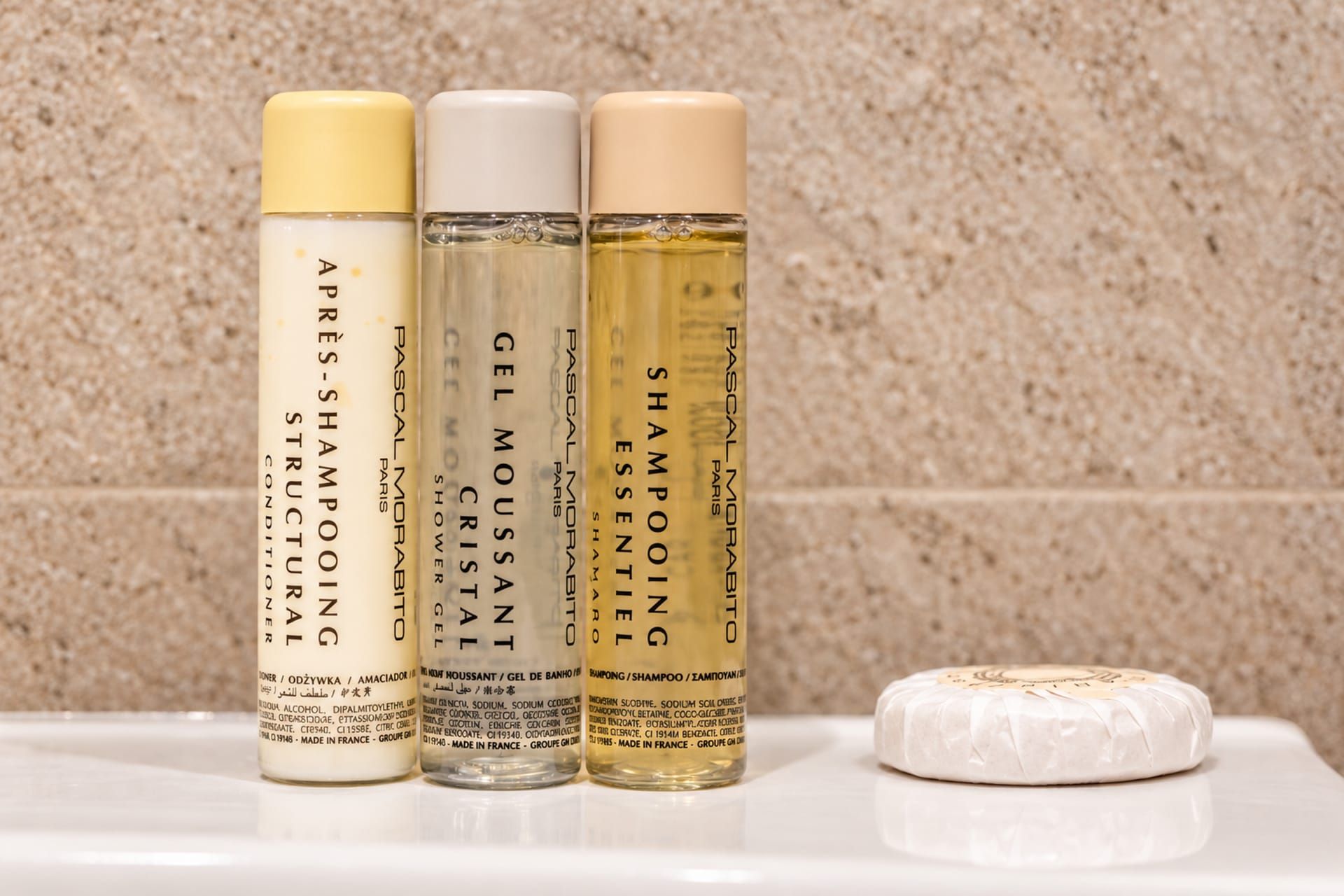 Four bottles of shampoo and a bar of soap on a white surface.