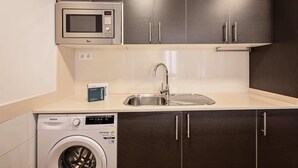 A compact kitchen with a microwave, sink, and washing machine. - Sweett | Symphonic Central 502 (Barcelona)