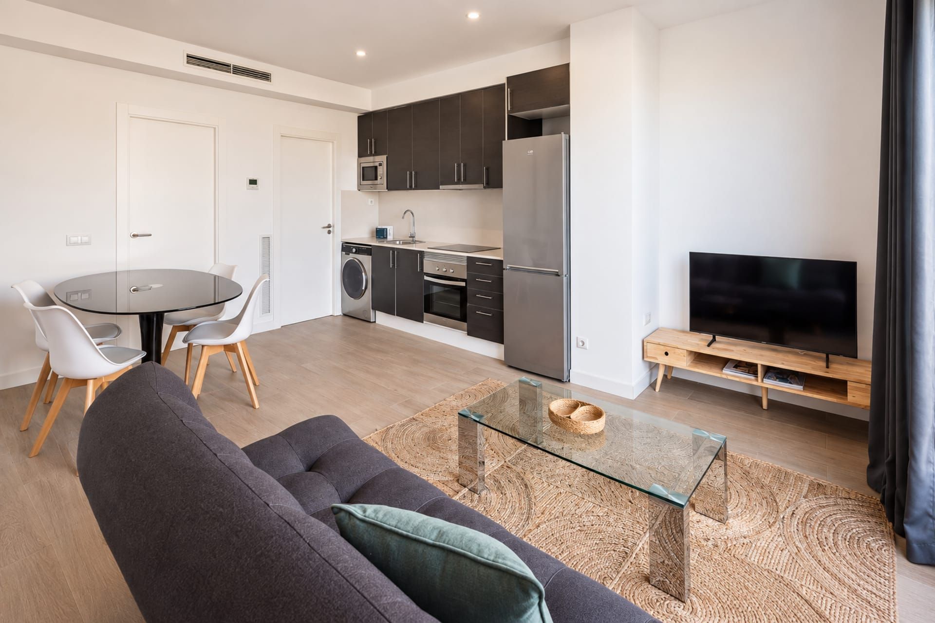 A modern living room with a sofa, a glass coffee table, and a television.