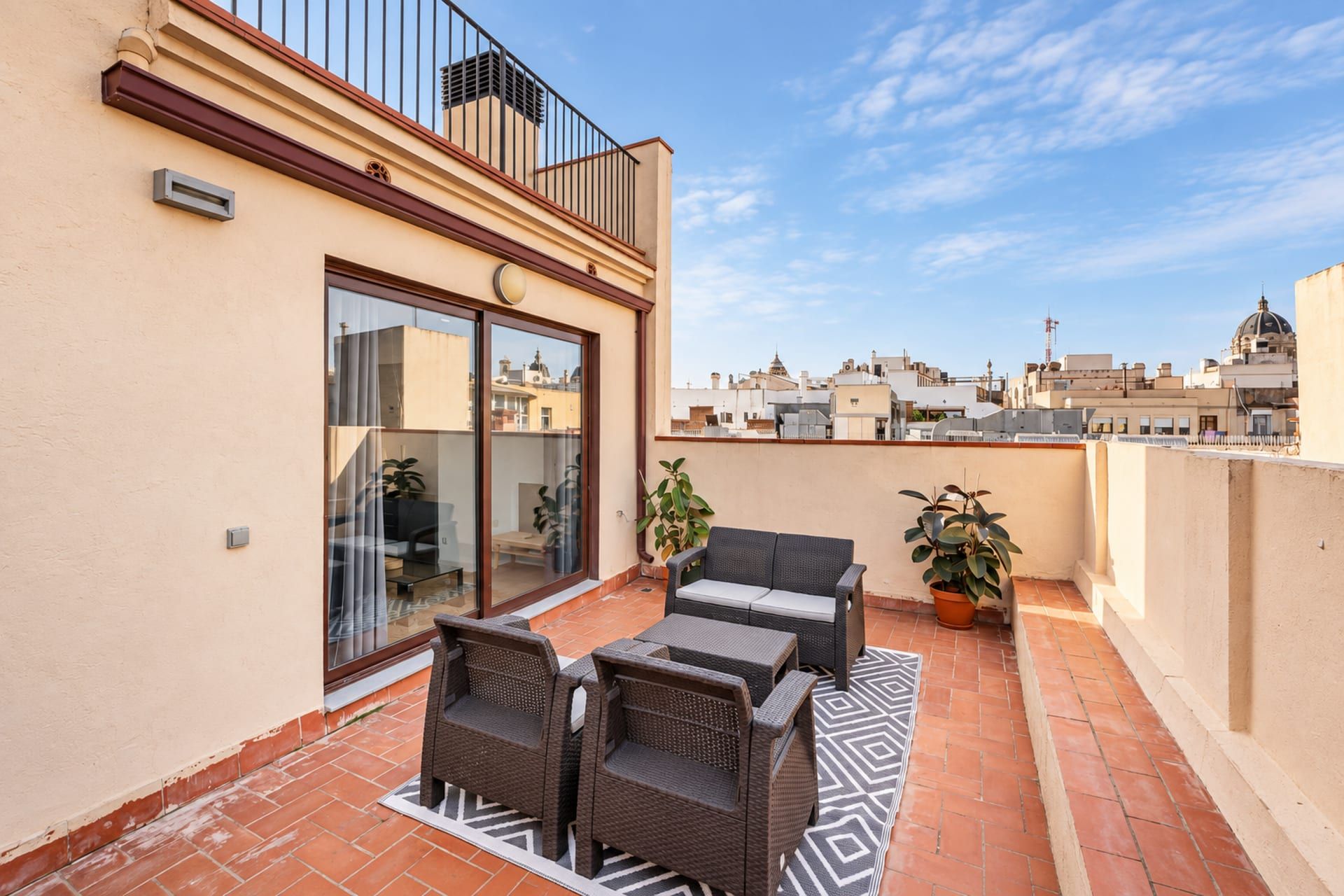 Terraza en la azotea con mobiliario exterior, puerta corrediza de vidrio y vistas panorámicas de la ciudad.