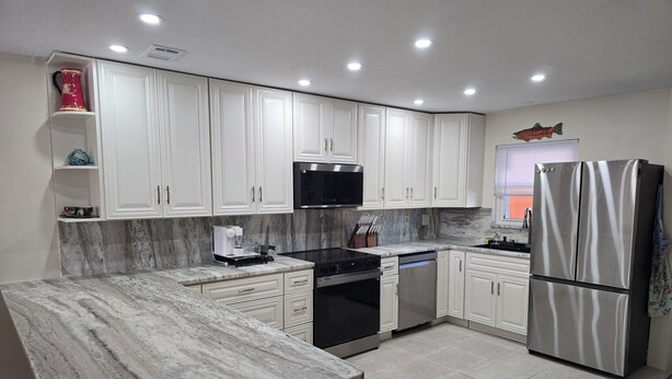 A modern kitchen with white cabinets, a stainless steel refrigerator, a microwave, and a coffee machine. - Cozy 2-bedroom condo with WiFi, AC in charming Punta Gorda (Punta Gorda)