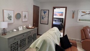Un salon avec un canapé en cuir marron, un meuble gris et des œuvres d’art encadrées accrochées aux murs.