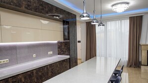 Een moderne keuken met een groot keukenblok, krukken, hanglampen en een ingebouwde bank.