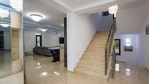 Een ruime woonkamer met een trap, een bank en een eethoek.