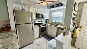 A compact kitchen with a stainless steel refrigerator, a microwave, an oven, and a sink. - Sandy Beach 326 in Fort Myers Beach (Fort Myers Beach)