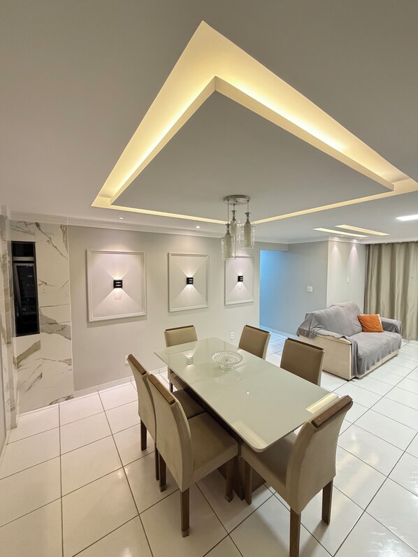 A modern dining area with a glass table, chairs, and pendant lighting.