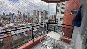 Un balcón con mesa y sillas, con vistas a un paisaje urbano con varios edificios.