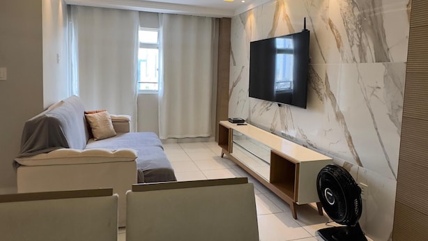 Una sala de estar moderna con un sofá, televisión y un ventilador.