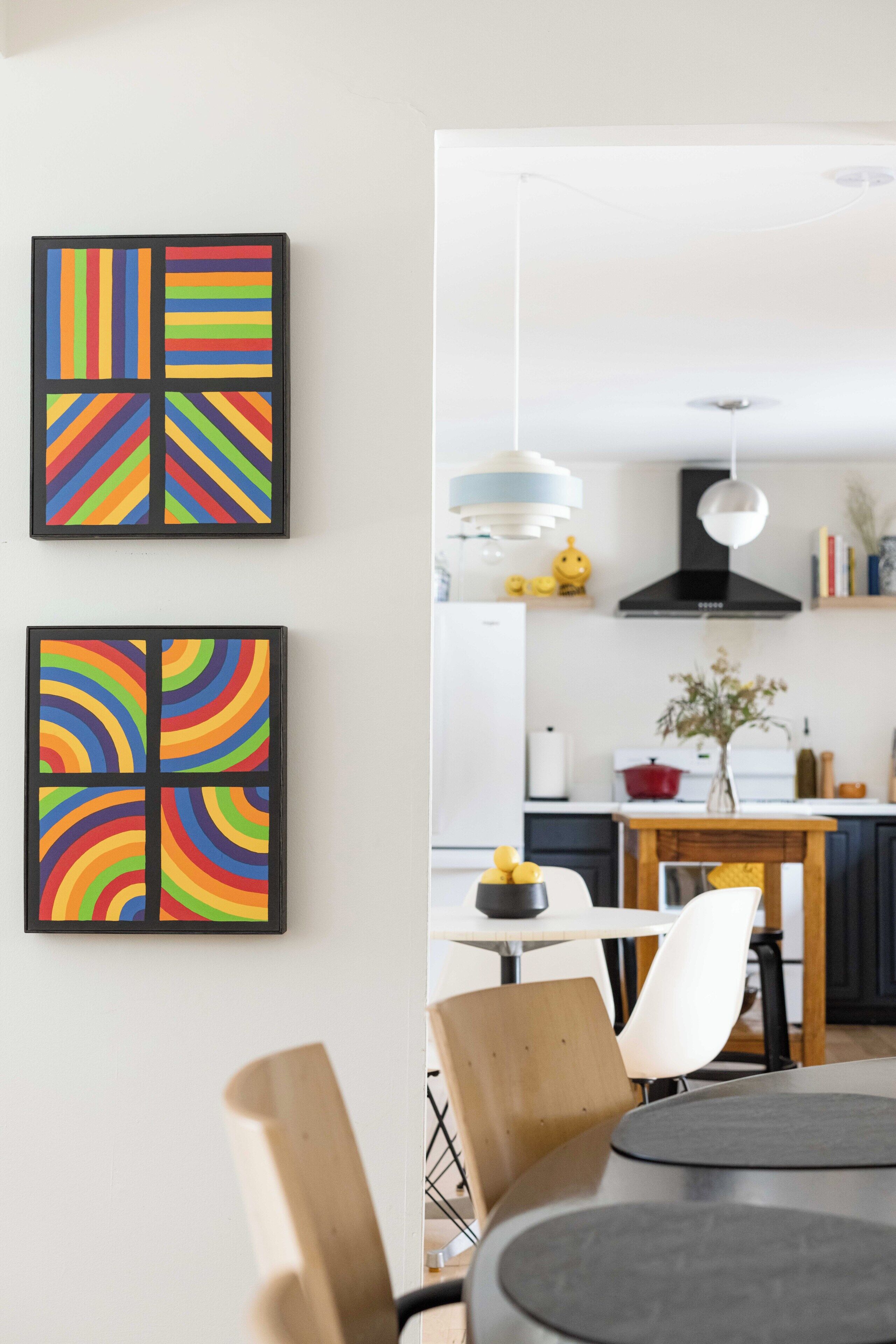 Eine moderne Küche mit Essbereich, in Schwarz-Weiß gehalten, mit einem runden Tisch und zwei gerahmten Kunstwerken an der Wand.