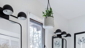 A modern bathroom with a white vanity, black fixtures, and framed artwork on the walls. - Contemporary Hudson Valley home (Staatsburg)