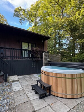 A wooden hot tub with benches, a wooden deck, and a house with a dark exterior. - Contemporary Hudson Valley home (Staatsburg)