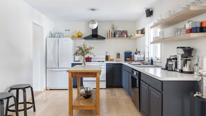 A modern kitchen with a central island, white appliances, and wooden accents. - Contemporary Hudson Valley home (Staatsburg)