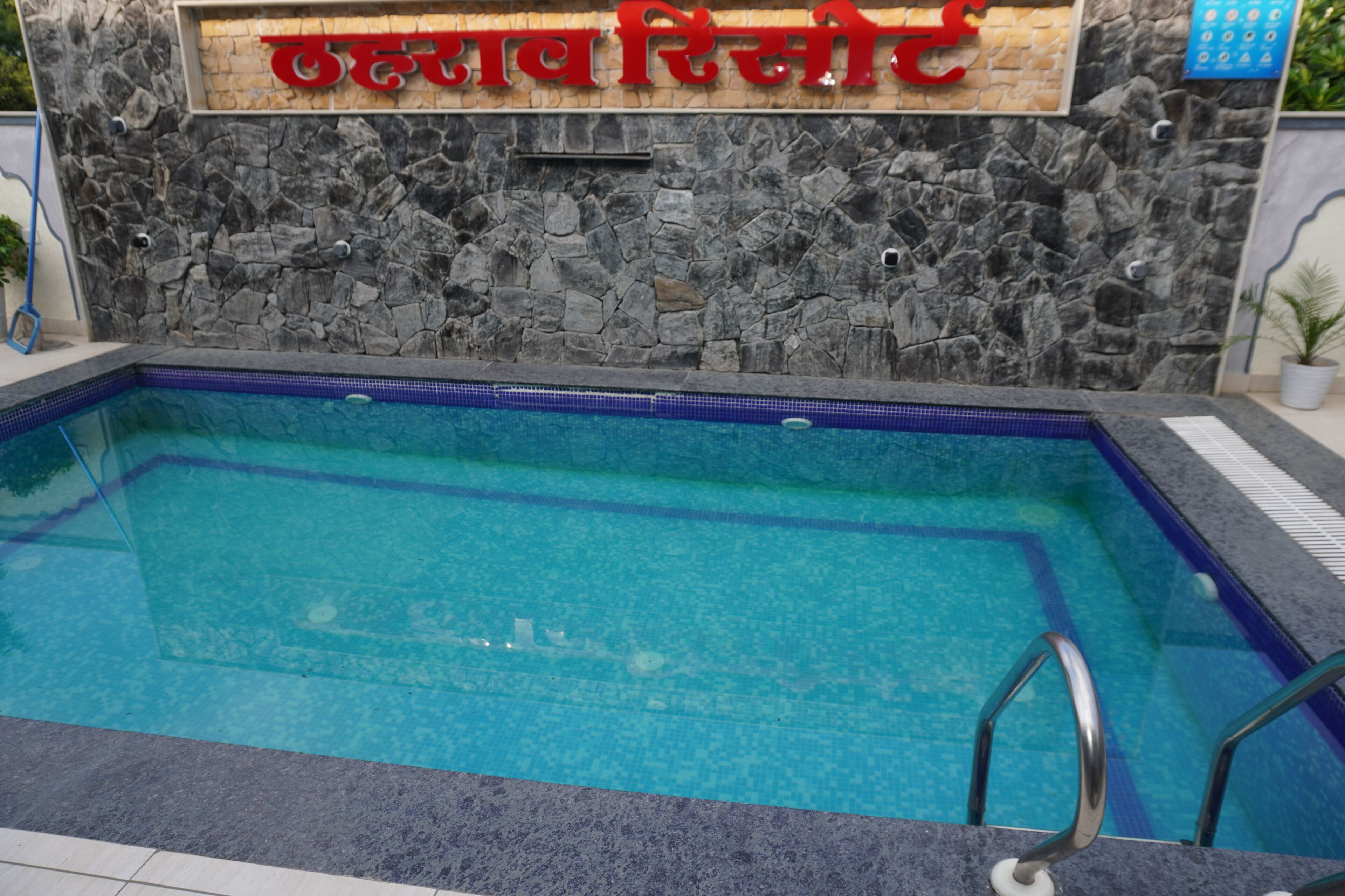 Una piscina con un muro de piedra y un cartel arriba.