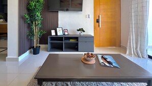 Ein modernes Wohnzimmer mit einem flachbildfernseher an der Wand, einer Holztür und einem großen Fenster mit Vorhängen.