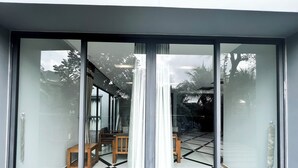 Eine moderne Villa mit einem großen Schiebeglastür, die zu einem Essbereich mit Schachbrettboden und Holzmöbeln führt.