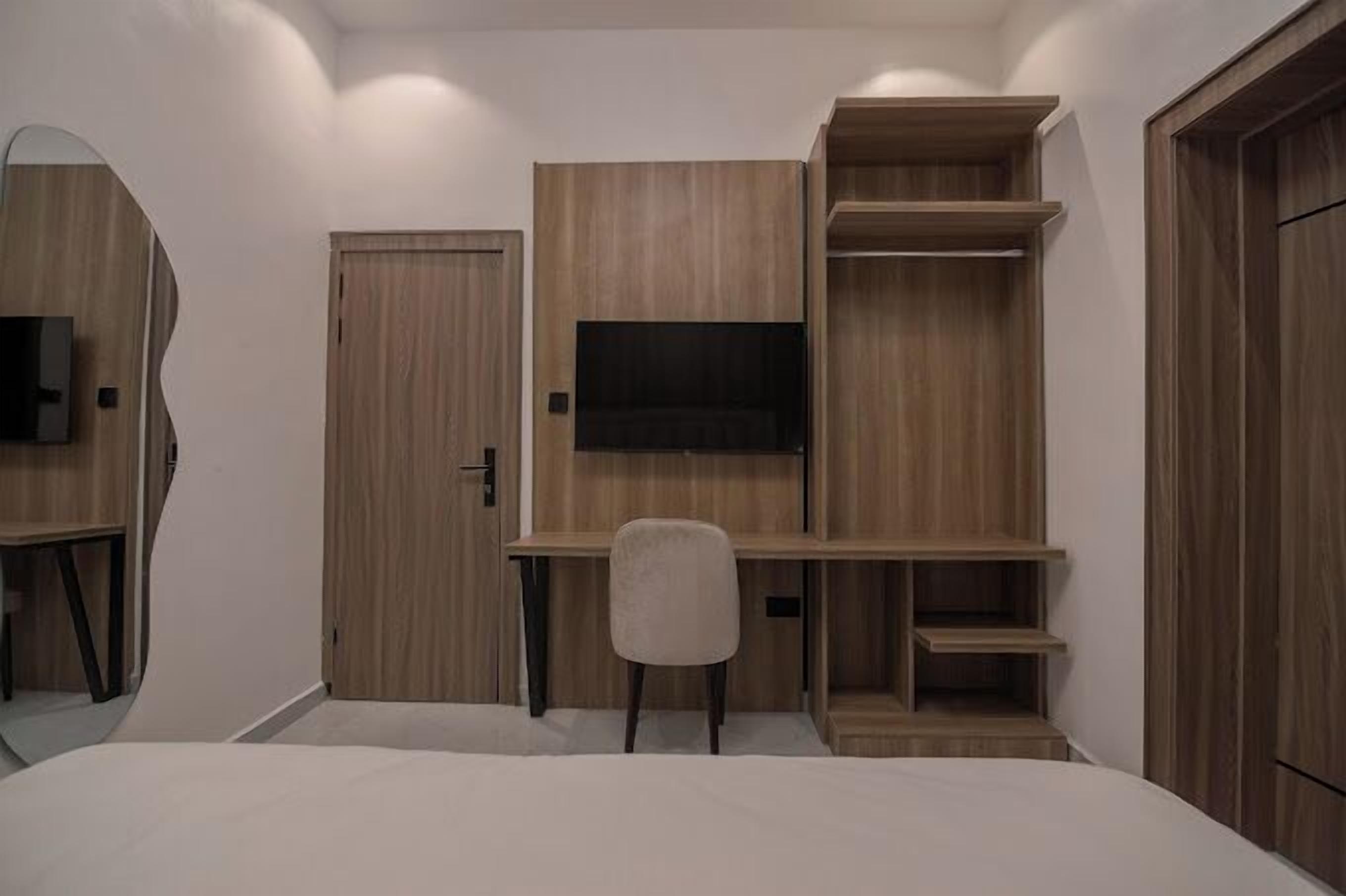 Une chambre à coucher comprenant un lit, un bureau, une chaise, un téléviseur et des étagères intégrées.