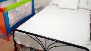 A bed with white bedding, a floral skirt, and a metal frame. - Ρετιρέ μεγάλο 3 δωμάτια.καθιστικό με βεράντα αγ. Κωσταντίνος με θέα το Πήλιο (Volos)