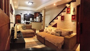 A cozy living room with a sofa set, a coffee table, and a staircase leading to an upper level. - LARGE PRIVATE SUITE WITH BALCONY AND CLOSE TO THE HISTORIC CENTER. PET FRIENDLY  (Caborê Paraty)
