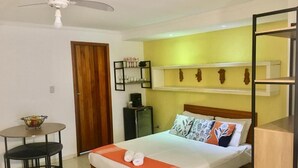 A neatly arranged bedroom with a bed, a small table with chairs, a ceiling fan, and a wardrobe. - LARGE PRIVATE SUITE WITH BALCONY AND CLOSE TO THE HISTORIC CENTER. PET FRIENDLY  (Caborê Paraty)