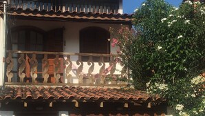A two-story house with a balcony, a tiled roof, and a wooden gate. - LARGE PRIVATE SUITE WITH BALCONY AND CLOSE TO THE HISTORIC CENTER. PET FRIENDLY  (Caborê Paraty)