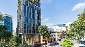 Ein modernes Gebäude mit Glasfassade, einem gut sichtbaren Eingang und einer Straße mit Autos und Fußgängern.