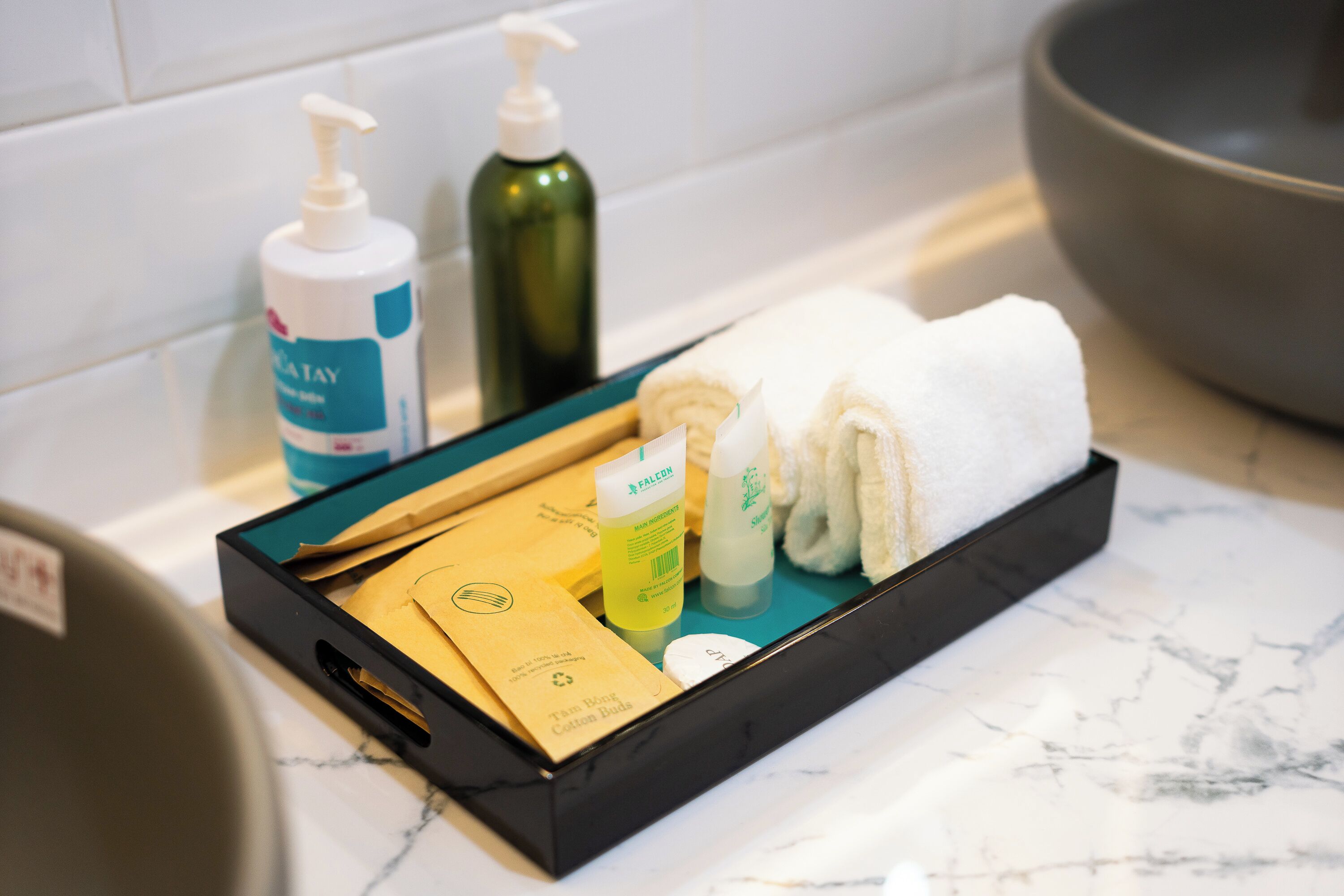A bathroom with a black tray holding toiletries, a towel, and a bath mat.